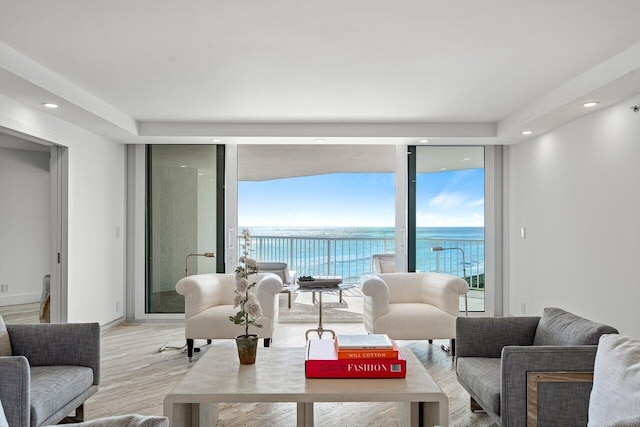 living room featuring a water view, light hardwood / wood-style floors, and a wall of windows