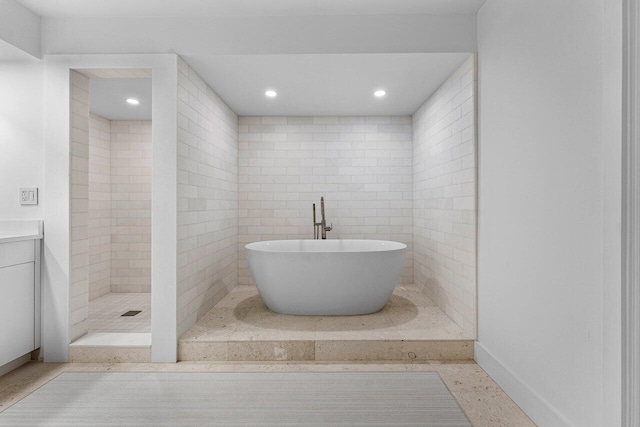 bathroom featuring vanity, independent shower and bath, and tile walls