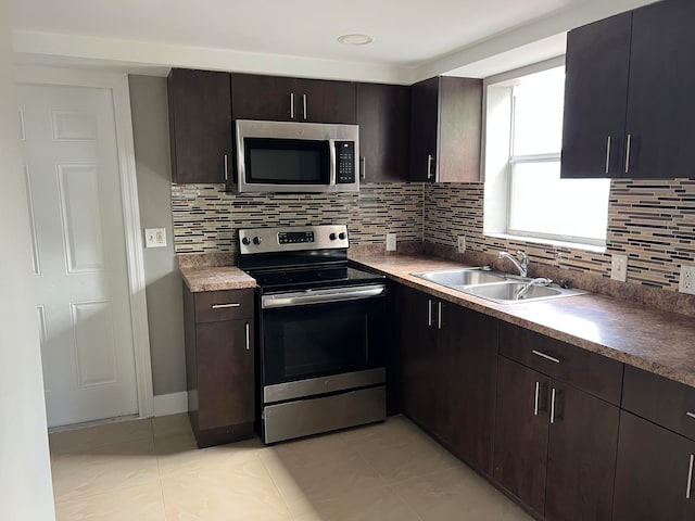 kitchen with dark brown cabinetry, light tile patterned floors, sink, tasteful backsplash, and stainless steel appliances