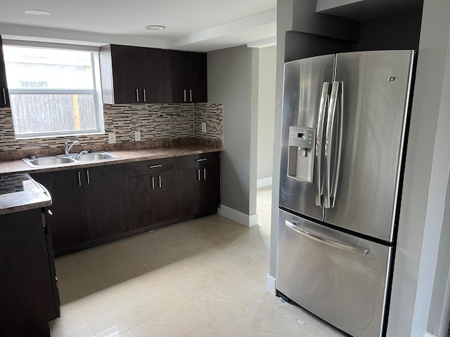 kitchen featuring stainless steel fridge, dark brown cabinets, sink, and tasteful backsplash