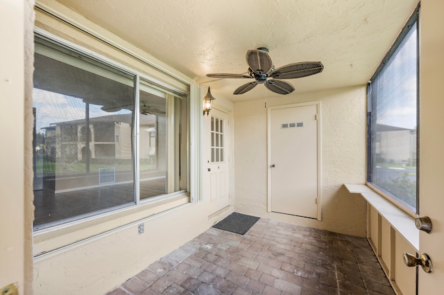 unfurnished sunroom featuring ceiling fan