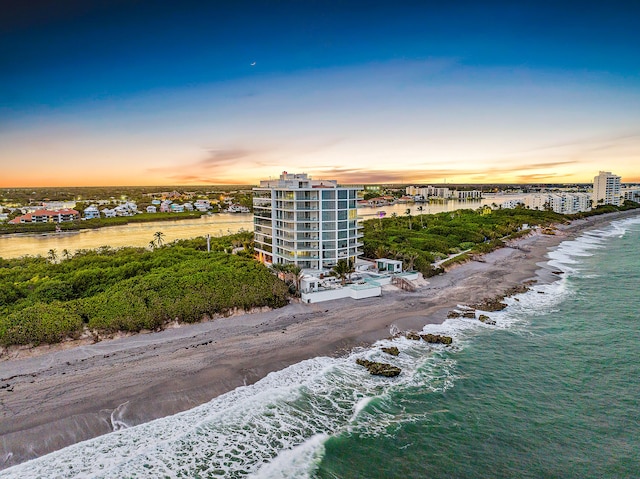 aerial view at dusk with a beach view and a water view