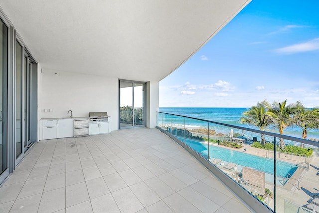 balcony with grilling area, a water view, sink, and exterior kitchen