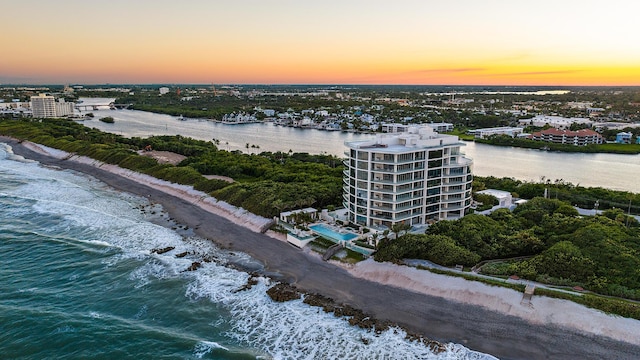 aerial view at dusk featuring a beach view and a water view