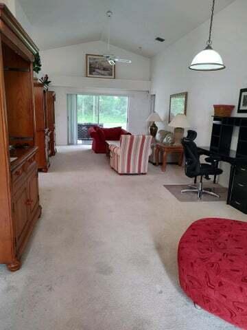 carpeted living room with lofted ceiling and ceiling fan