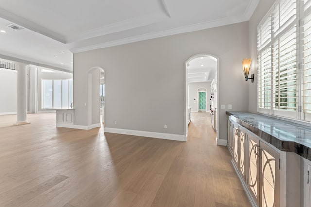 unfurnished living room featuring light wood-type flooring, ornamental molding, and a tray ceiling