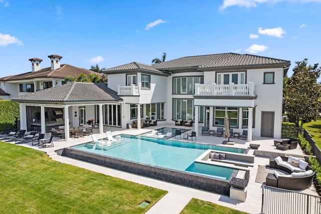 rear view of house with a lawn, outdoor lounge area, a balcony, and a patio