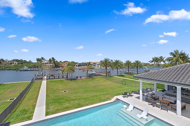 view of swimming pool featuring a water view, a lawn, and a patio