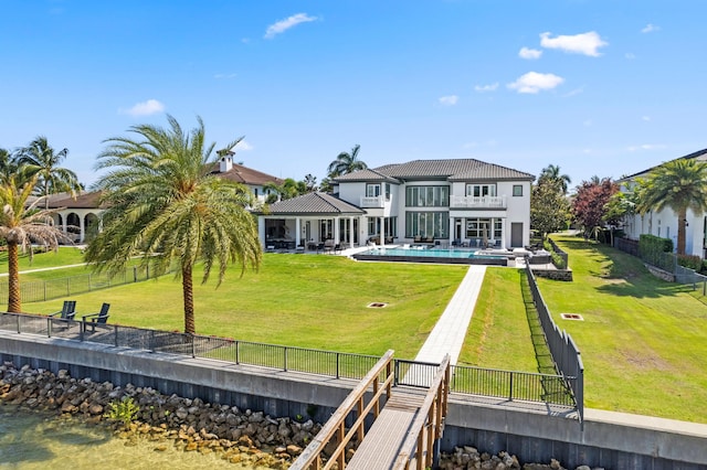 rear view of property featuring a fenced in pool, a lawn, a balcony, and a patio