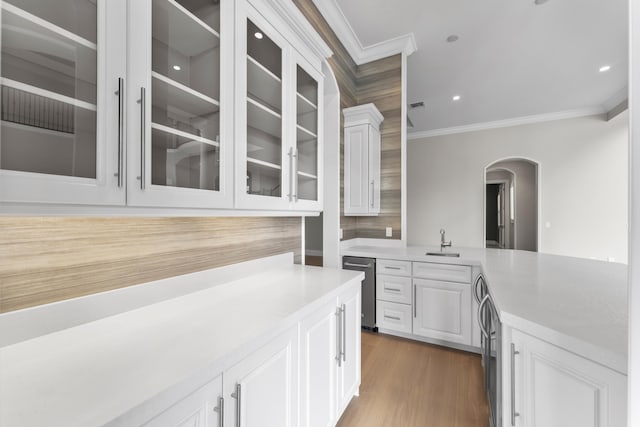 kitchen with dark wood-type flooring, white cabinetry, crown molding, and sink