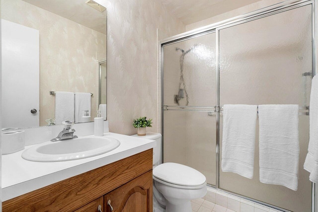 bathroom with vanity, toilet, tile patterned floors, and a shower with door