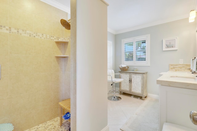 bathroom featuring tile patterned flooring, a tile shower, crown molding, and vanity