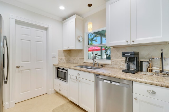 kitchen with pendant lighting, sink, stainless steel appliances, light stone countertops, and white cabinets