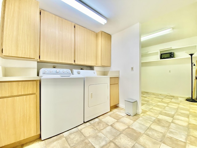 clothes washing area with separate washer and dryer and cabinets