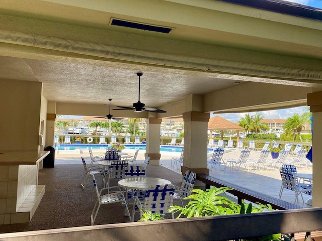 view of patio with ceiling fan and a community pool