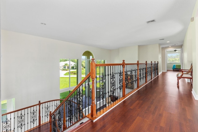 corridor featuring baseboards, an upstairs landing, wood finished floors, and visible vents