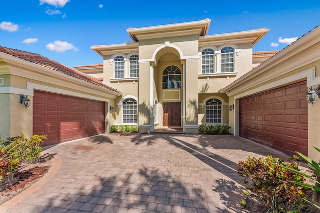 mediterranean / spanish home featuring decorative driveway, an attached garage, and stucco siding
