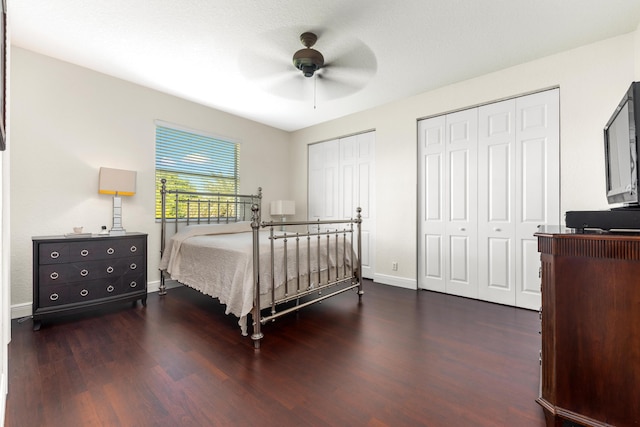 bedroom with ceiling fan, baseboards, multiple closets, and wood finished floors