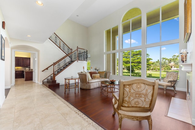 living room featuring stairs, baseboards, a high ceiling, recessed lighting, and arched walkways