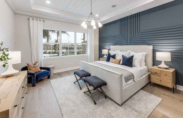 bedroom featuring ornamental molding, light hardwood / wood-style floors, a raised ceiling, and a chandelier