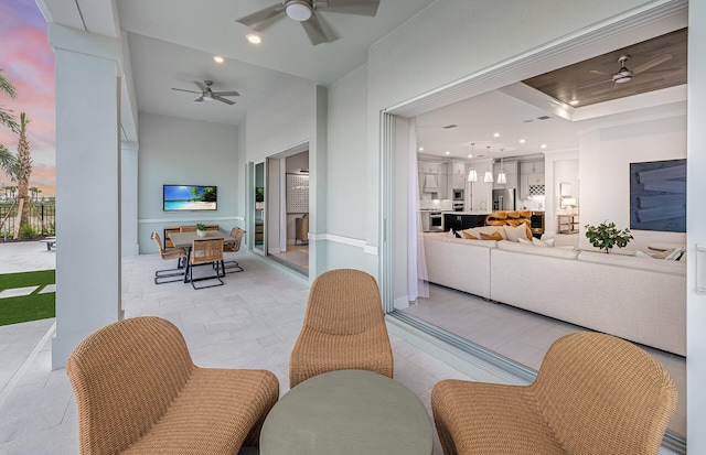 living room featuring ceiling fan and a raised ceiling