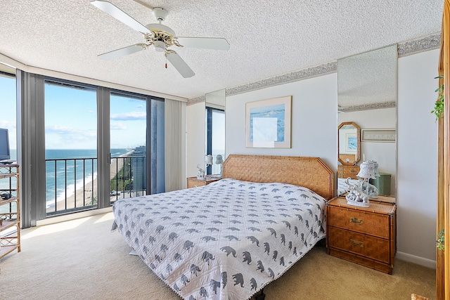 bedroom with a water view, access to exterior, a textured ceiling, and ceiling fan