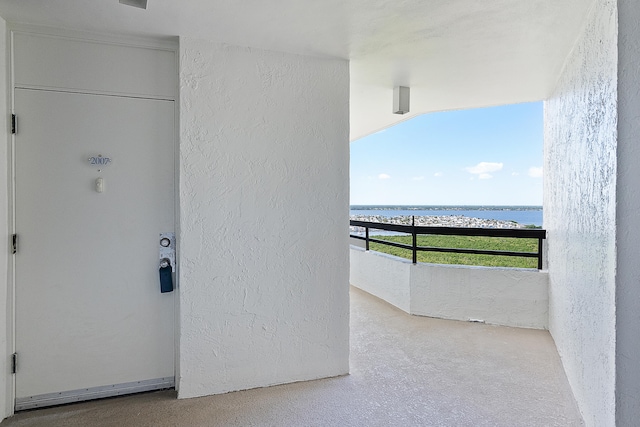 view of exterior entry featuring a water view and a balcony