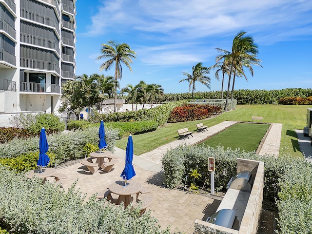 view of property's community featuring a lawn and a patio area