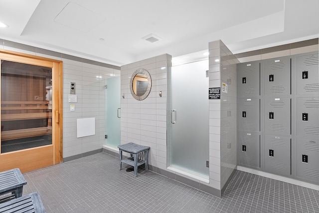 bathroom featuring tile walls, a shower with shower door, and tile patterned floors