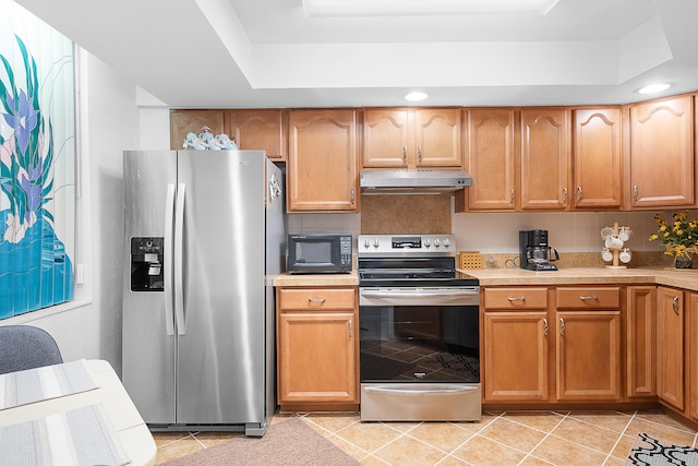 kitchen with light tile patterned floors, appliances with stainless steel finishes, a tray ceiling, and tasteful backsplash