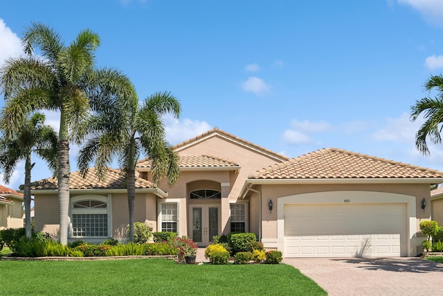 mediterranean / spanish-style house featuring a garage and a front lawn