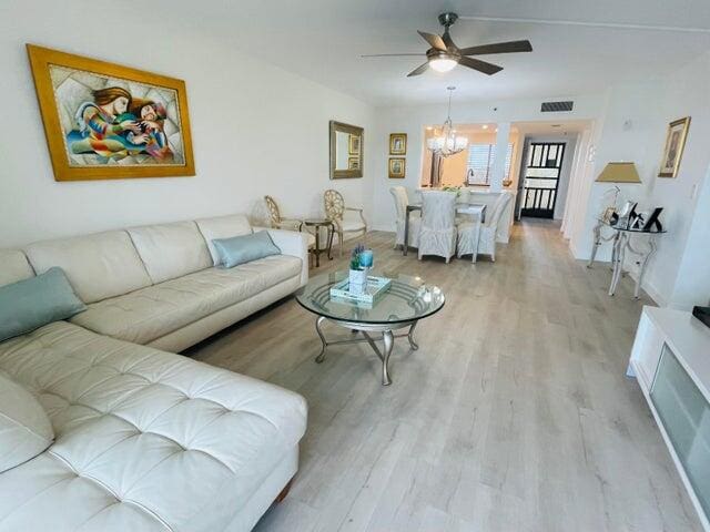 living room with light hardwood / wood-style flooring and ceiling fan with notable chandelier