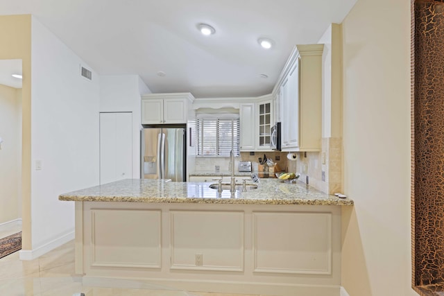 kitchen with decorative backsplash, stainless steel appliances, kitchen peninsula, and light stone countertops