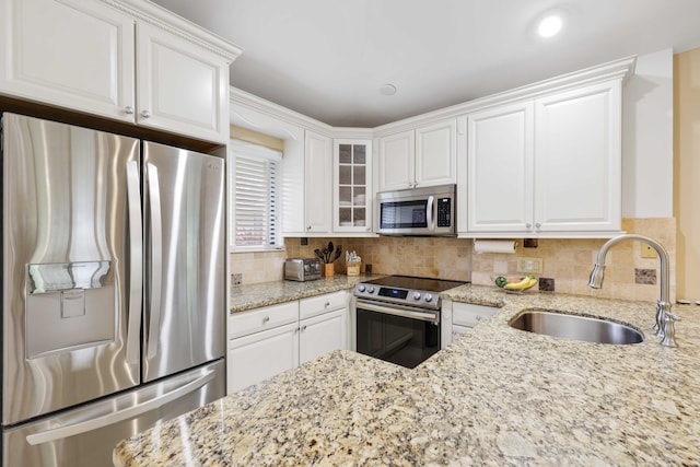 kitchen with light stone countertops, white cabinetry, sink, and appliances with stainless steel finishes