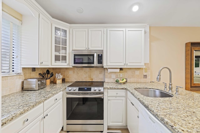 kitchen featuring white cabinetry, sink, stainless steel appliances, and light stone counters