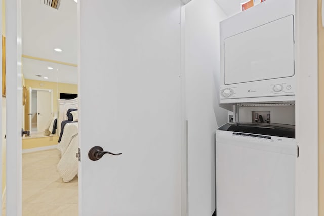 laundry room featuring stacked washer and dryer and light tile patterned flooring