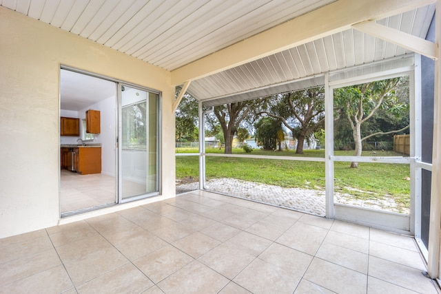 unfurnished sunroom featuring a wealth of natural light and vaulted ceiling with beams