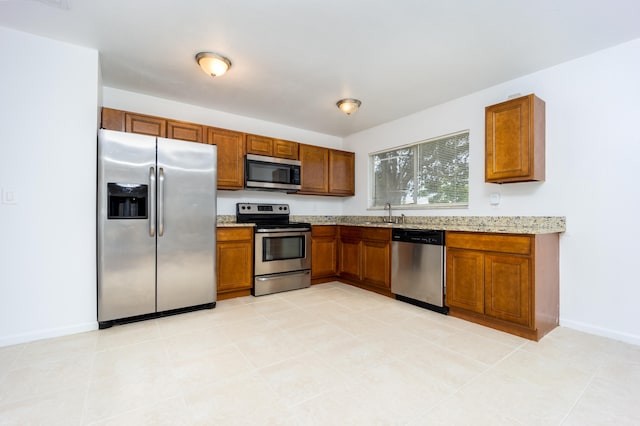 kitchen featuring light stone countertops, appliances with stainless steel finishes, and light tile patterned floors