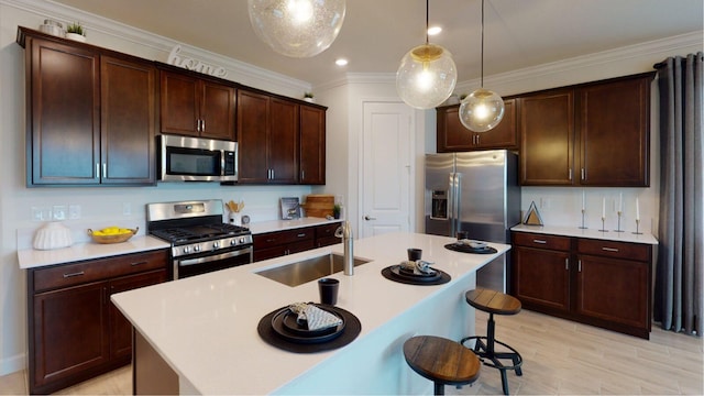 kitchen with sink, stainless steel appliances, hanging light fixtures, and an island with sink