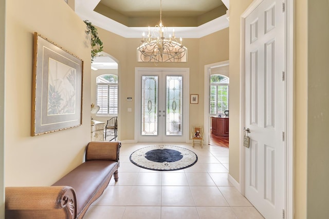 foyer featuring a tray ceiling, light tile patterned floors, french doors, and a notable chandelier