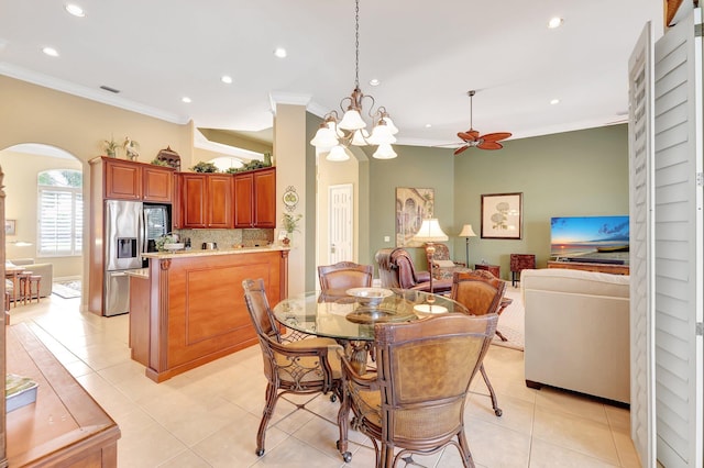 dining space with crown molding, ceiling fan with notable chandelier, and light tile patterned floors