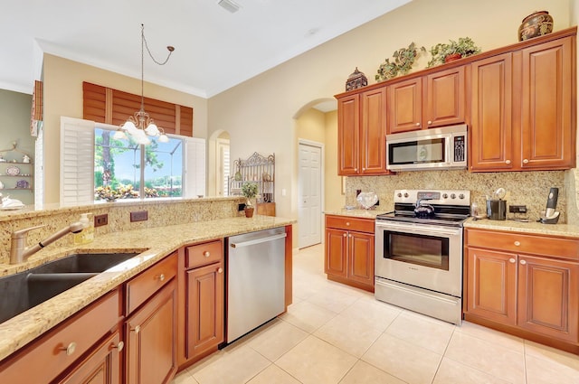 kitchen with a chandelier, light stone counters, decorative backsplash, stainless steel appliances, and decorative light fixtures