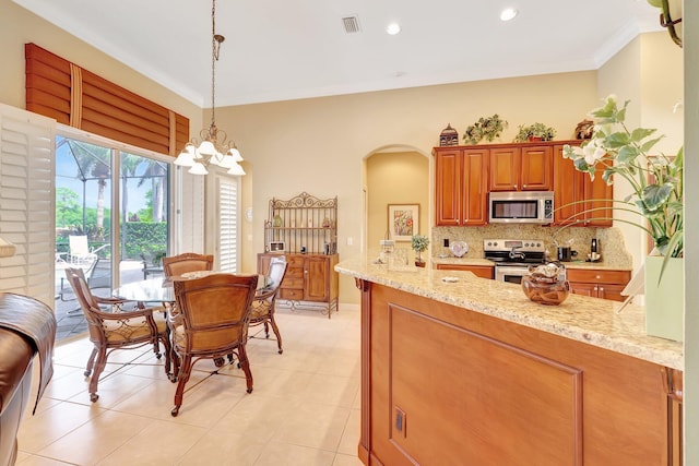 kitchen featuring light stone counters, tasteful backsplash, stainless steel appliances, decorative light fixtures, and crown molding