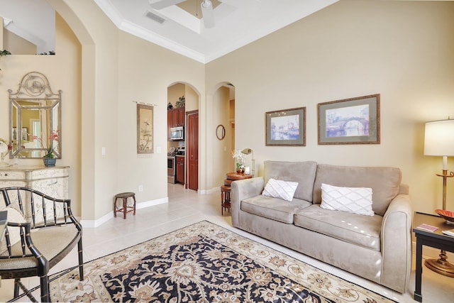 living room featuring ornamental molding, a towering ceiling, ceiling fan, and light tile patterned flooring