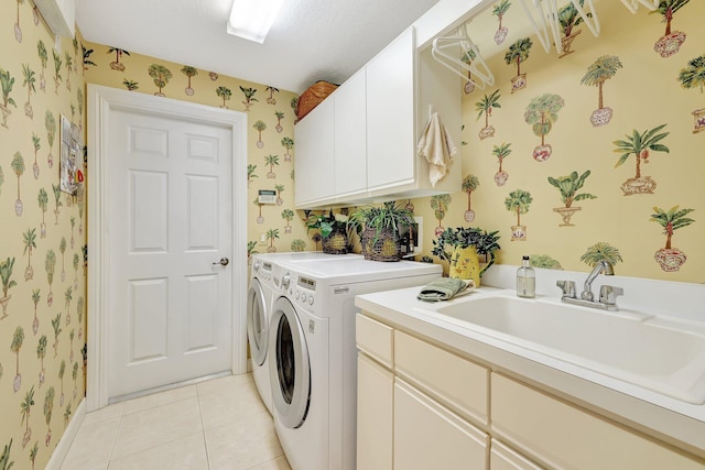 laundry room featuring light tile patterned floors, a textured ceiling, cabinets, washer and clothes dryer, and sink