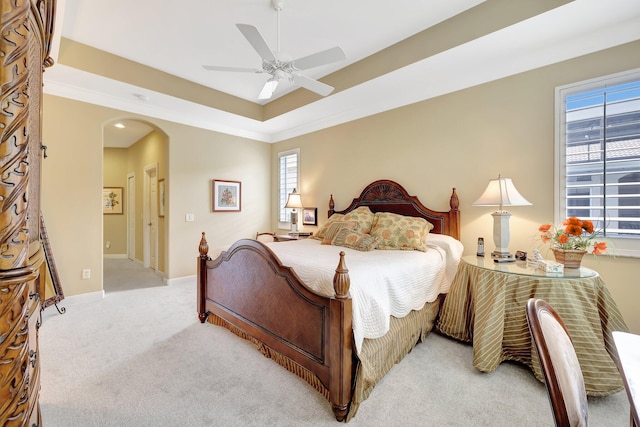 carpeted bedroom featuring ceiling fan and a tray ceiling