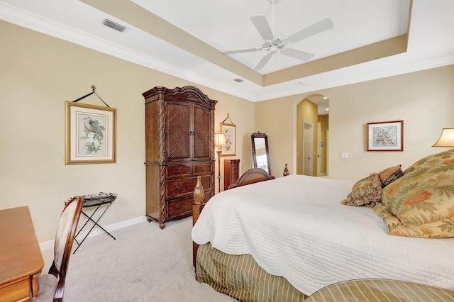 bedroom featuring ceiling fan, light colored carpet, a raised ceiling, and crown molding