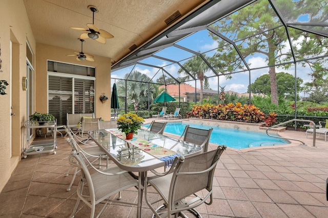 view of swimming pool with glass enclosure, ceiling fan, and a patio area