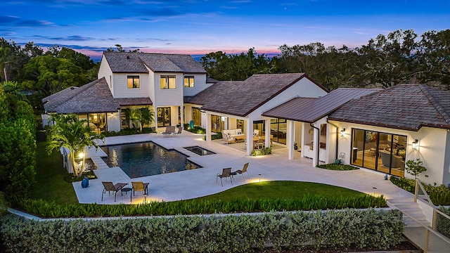 back house at dusk featuring a fenced in pool, a yard, a patio, and an outdoor hangout area