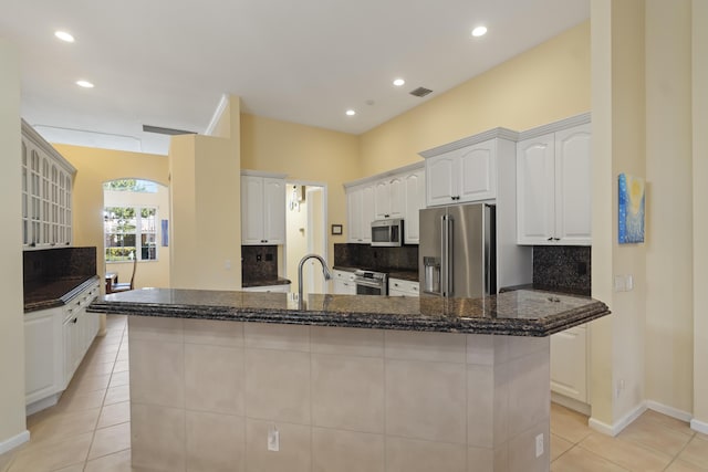 kitchen featuring white cabinetry, dark stone counters, stainless steel appliances, and decorative backsplash